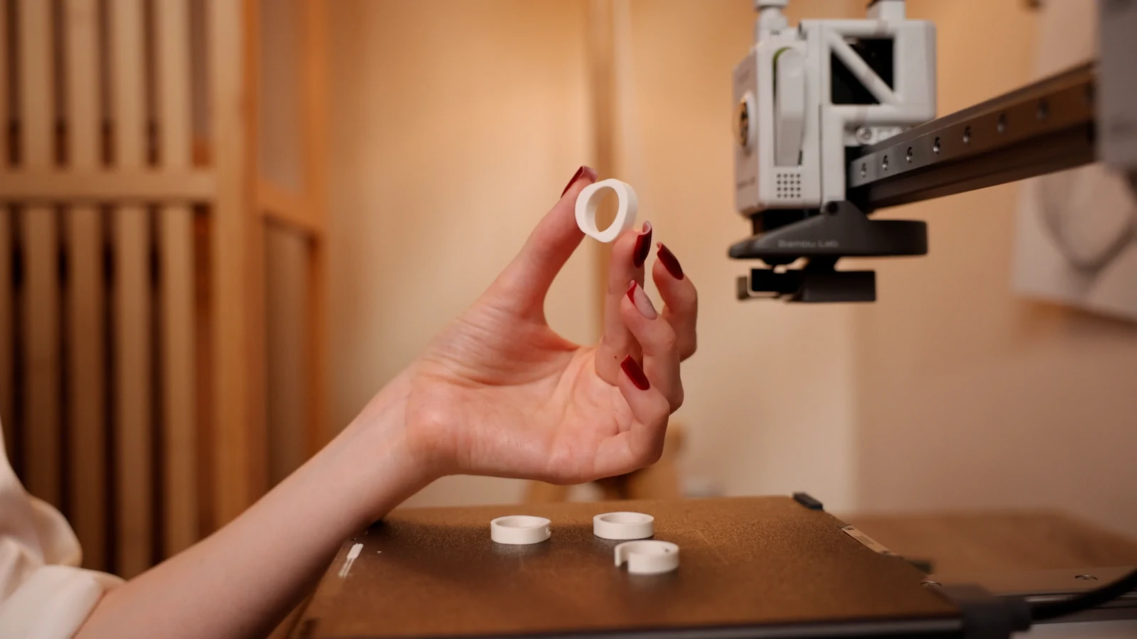 A hand holding a freshly printed ring beside the printer.